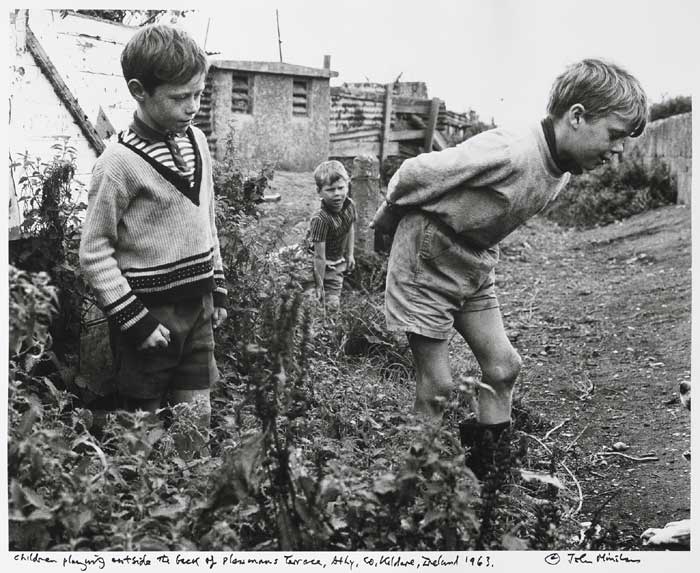 CHILDREN PLAYING OUTSIDE THE BACK OF PLOUGHMAN'S TERRACE, ATHY, COUNTY KILDARE, 1963 by John Minihan (b.1946) at Whyte's Auctions